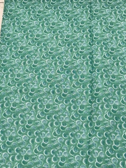Green and white half circle on green bluish fabric