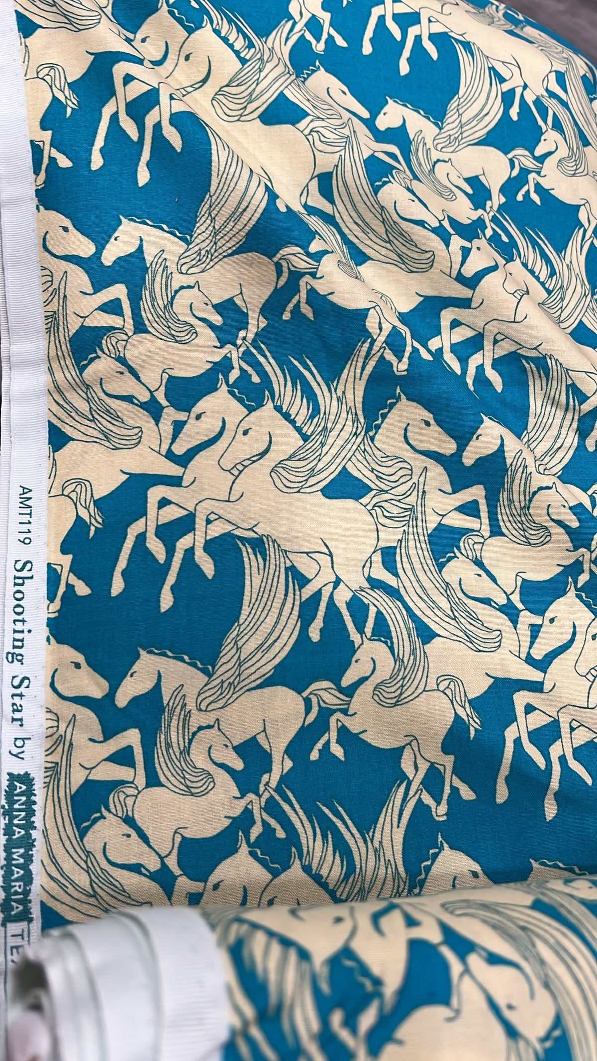 Shooting Star Mythology Pegasus fabric by Anna Maria, folded to show the horse print texture in cream on turquoise
