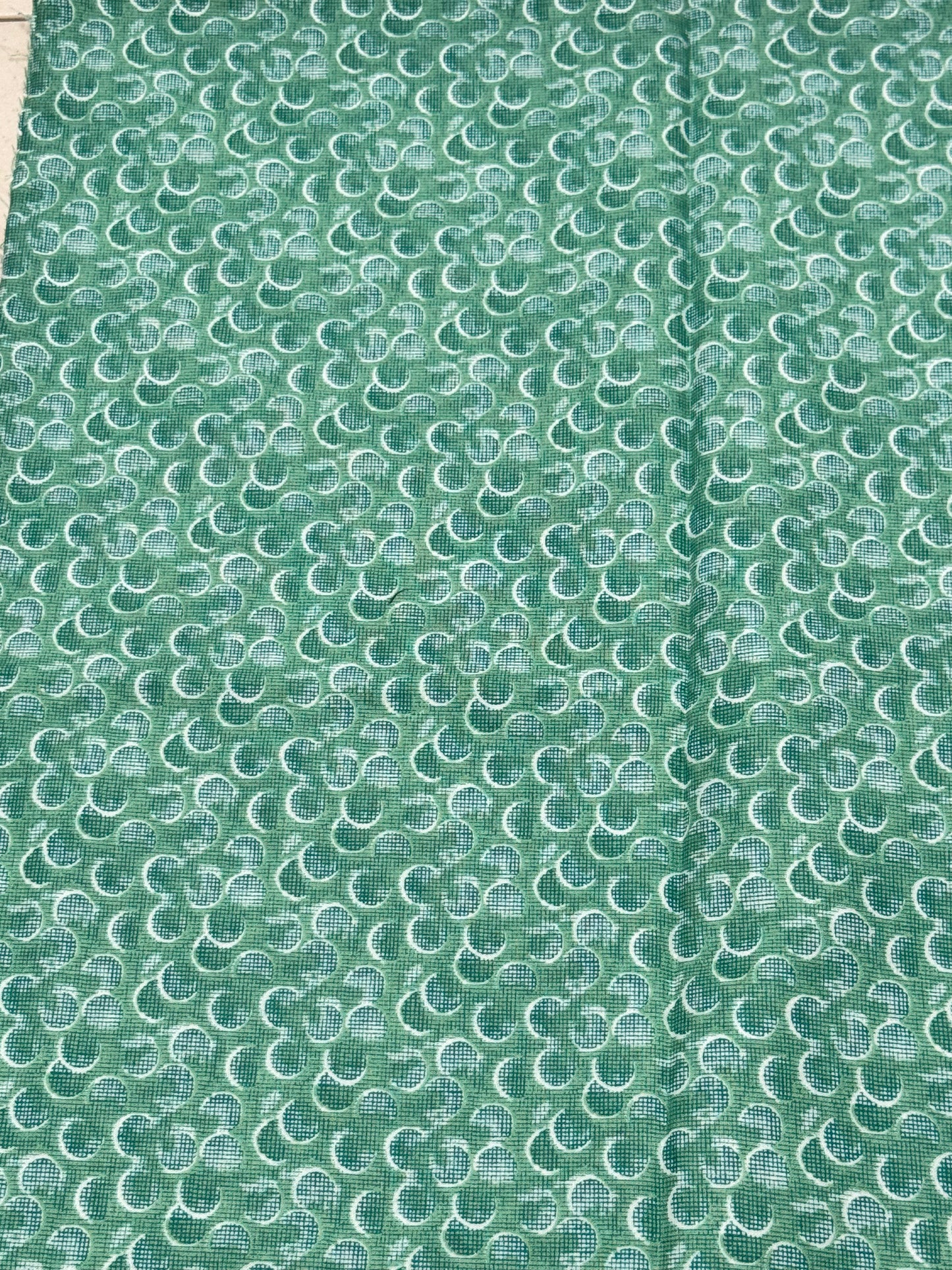 Green and white half circle on green bluish fabric